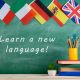 flags of Spain, France, Great Britain and other countries, blackboard with text "Learn a new language!", books and chancellery